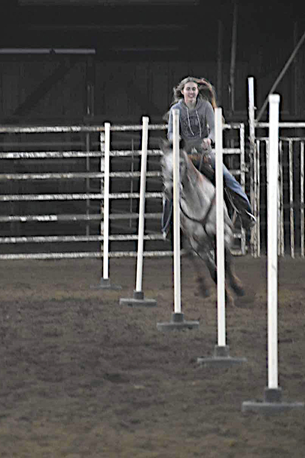 Female horse rider racing between poles
